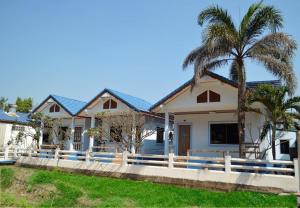 a house with a white fence and palm trees at Pama Resort in Rayong