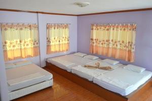 two beds in a room with two windows at Pama Resort in Rayong