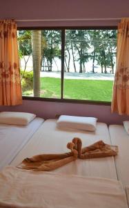 two beds in a room with a large window at Pama Resort in Rayong