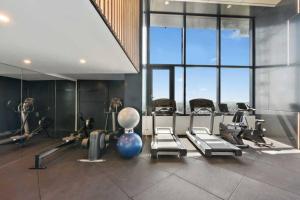 a gym with cardio equipment in a large room with windows at Lvl 24 Family apartment in the heart of CBD by Stylish Stays in Brisbane