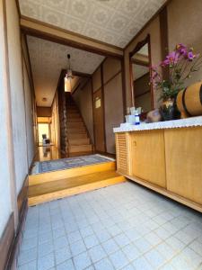 ゲストハウス陽だまりの宿 في Tomi: مدخل مبنى به درج و مزهرية من الزهور