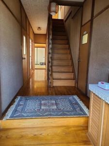 pasillo con escalera y alfombra en el suelo en ゲストハウス陽だまりの宿, en Tomi