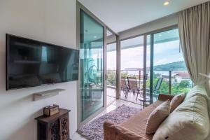 a living room with a couch and a large tv at Oceana Sea View Apartments - Kamala Beach in Kamala Beach
