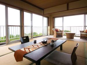 un soggiorno con tavolo, sedie e finestre di Iseebisou a Ibusuki