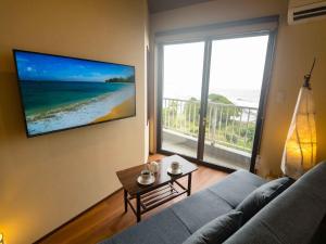 a living room with a couch and a tv on a wall at Iseebisou in Ibusuki