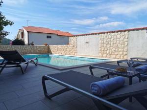 eine Terrasse mit einem Pool, 2 Stühlen und einem Tisch in der Unterkunft Apartments Miranda in Lopar