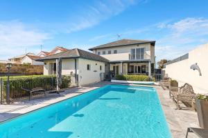 a swimming pool in front of a house at Beachfront Family Favourite Home with Pool & Views in Mandurah