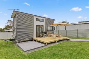 a tiny house with a deck and an umbrella at Husky Tiny Home by Experience Jervis Bay in Huskisson