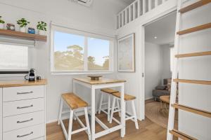 a small kitchen with a table and two stools at Husky Tiny Home by Experience Jervis Bay in Huskisson