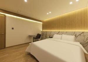 1 dormitorio con 1 cama blanca grande y 1 silla en Gwangju Brown Dot Chungjang en Gwangju