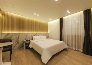 Un dormitorio con una gran cama blanca y una mesa en Gwangju Brown Dot Chungjang en Gwangju