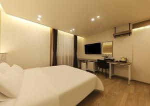 a hotel room with a white bed and a desk at Gwangju Brown Dot Chungjang in Gwangju