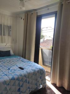 1 dormitorio con 1 cama y puerta corredera de cristal en Tardeli Suite dos anjos com sacada, en Arraial do Cabo