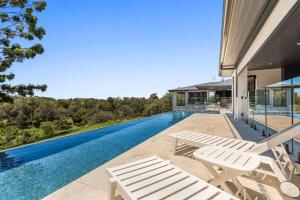 a swimming pool with two white chairs and a house at 145 Western Adults ONLY in Montville