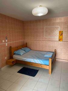 a small bed in a room with a tiled wall at Studio « Ti Thon » avec vu magnifique sur la Montagne du Vauclin in Le Vauclin