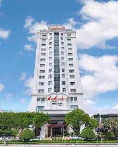 a tall white building with red flags on it at Ha Long Dream Hotel in Ha Long