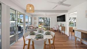Sunset Sails Taylors Beach NSW في Taylors Beach: غرفة طعام وغرفة معيشة مع طاولة وكراسي