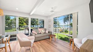 a living room with a couch and chairs and windows at Sunset Sails Taylors Beach NSW in Taylors Beach