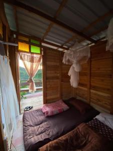 a bedroom with a bed in a room with a window at Khaokhopimphupha farmstay เขาค้อพิมภูผาฟาร์มสเตย์ ไม่มีไฟฟ้า น้ำจากน้ำตกธรรมชาติ Low cabon with Sustainability cares in Ban Non Na Yao