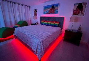 1 dormitorio con 1 cama con iluminación de color rojo en Beachfront Tropical Tantra Apartment, en San Juan