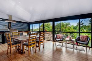 a dining room with a table and chairs and windows at A Family Home Away From Home in Gold Coast