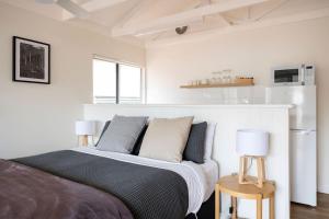 a bedroom with a bed with two lamps and a refrigerator at Nornalup Riverside Chalets in Nornalup +49 photos