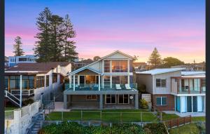 a home in the suburbs of sydney at sunset at Sea View - Absolute Beachfront Shellharbour in Shellharbour