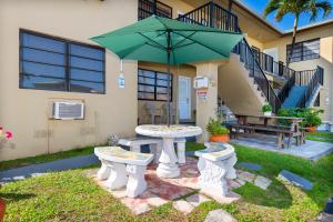 a patio with a table and a green umbrella at Tropic Isle Hotel & Apartment in Hollywood