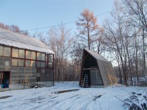 a small building in the snow next to a house at Niseko Shirokuma Cottage in Niseko