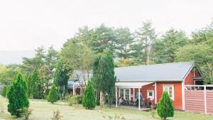 una casa roja con un hombre parado frente a ella en PICA Fujisaiko, en Fujikawaguchiko