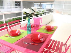 einem rosa Tisch mit roten Platten und einer Vase aus Blumen in der Unterkunft Appartement La Rochelle, 2 pièces, 4 personnes - FR-1-246-11 in La Rochelle