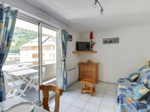 1 Schlafzimmer mit einem Bett und einem Balkon mit einem TV in der Unterkunft Studio Luz-Saint-Sauveur, 1 pièce, 4 personnes - FR-1-402-59 in Luz-Saint-Sauveur