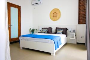 a white bedroom with a bed with blue sheets and pillows at Villa Grain de café, 3 chambres piscine accès plage in Trou aux Biches