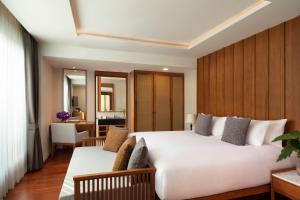 a bedroom with a large white bed and a desk at Avani Ao Nang Cliff Krabi Resort in Ao Nang Beach