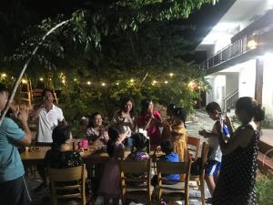 un grupo de personas sentadas alrededor de una mesa por la noche en Mộc Lam Homestay, en Xóm Chum Găng