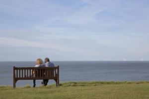 a man and woman sitting on a bench looking at the ocean at The Marine in Whitstable