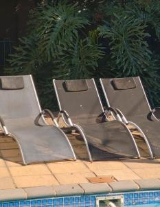 three empty chairs sitting next to a swimming pool at Constantia Manor Guest House in Pretoria