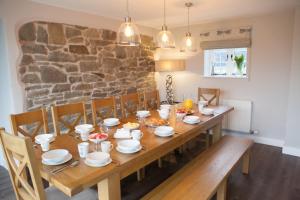 a dining room with a wooden table and a stone wall at Roundton House in Chirbury