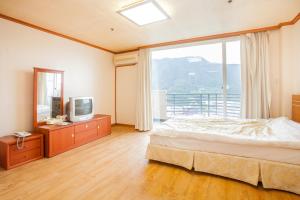 a bedroom with a bed and a large window at Bugok Ilsung Condo in Changnyeong