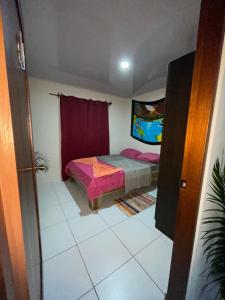 a small bedroom with a bed and a red curtain at Around Juan Santa María in Alajuela City