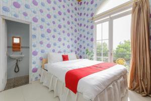 a bedroom with a bed with a red and white blanket at RedDoorz at Villa Puncak Tidar in Malang