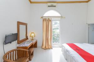 1 dormitorio con cama, espejo y TV en RedDoorz at Villa Puncak Tidar, en Malang