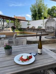 una mesa con un plato de comida y una botella de vino en Boutiquehotel Goldhahn Bio Sport & Wellness en Aalen