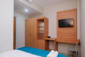 a bedroom with a bed and a tv on a wall at Sans Hotel Tiga Putri Semarang by RedDoorz in Semarang