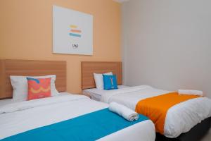 a bedroom with two beds with colorful pillows at Sans Hotel Tiga Putri Semarang by RedDoorz in Semarang