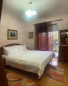 Un dormitorio con una gran cama blanca y una ventana en Korca Central Flat, en Korçë