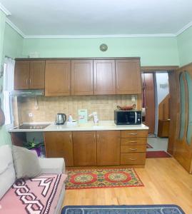 una cocina con armarios de madera y un sofá en una habitación en Korca Central Flat, en Korçë