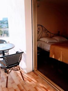 a bedroom with a bed and a table and a window at Hôtel Restaurant Brasilia in Cagnes-sur-Mer