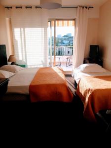 two beds in a room with a large window at Hôtel Restaurant Brasilia in Cagnes-sur-Mer