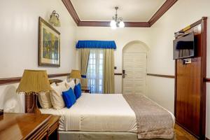 a bedroom with a bed and a desk and a tv at Citrus Chambers Mahabaleshwar in Mahabaleshwar
